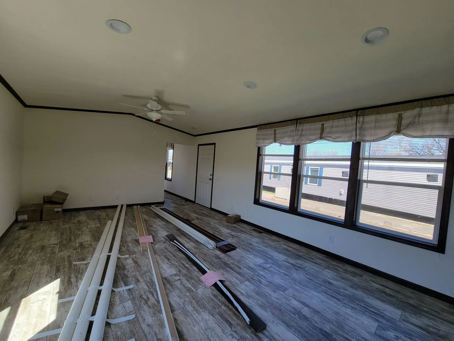 Interior view of a room with unfinished flooring, windows, and a ceiling fan.