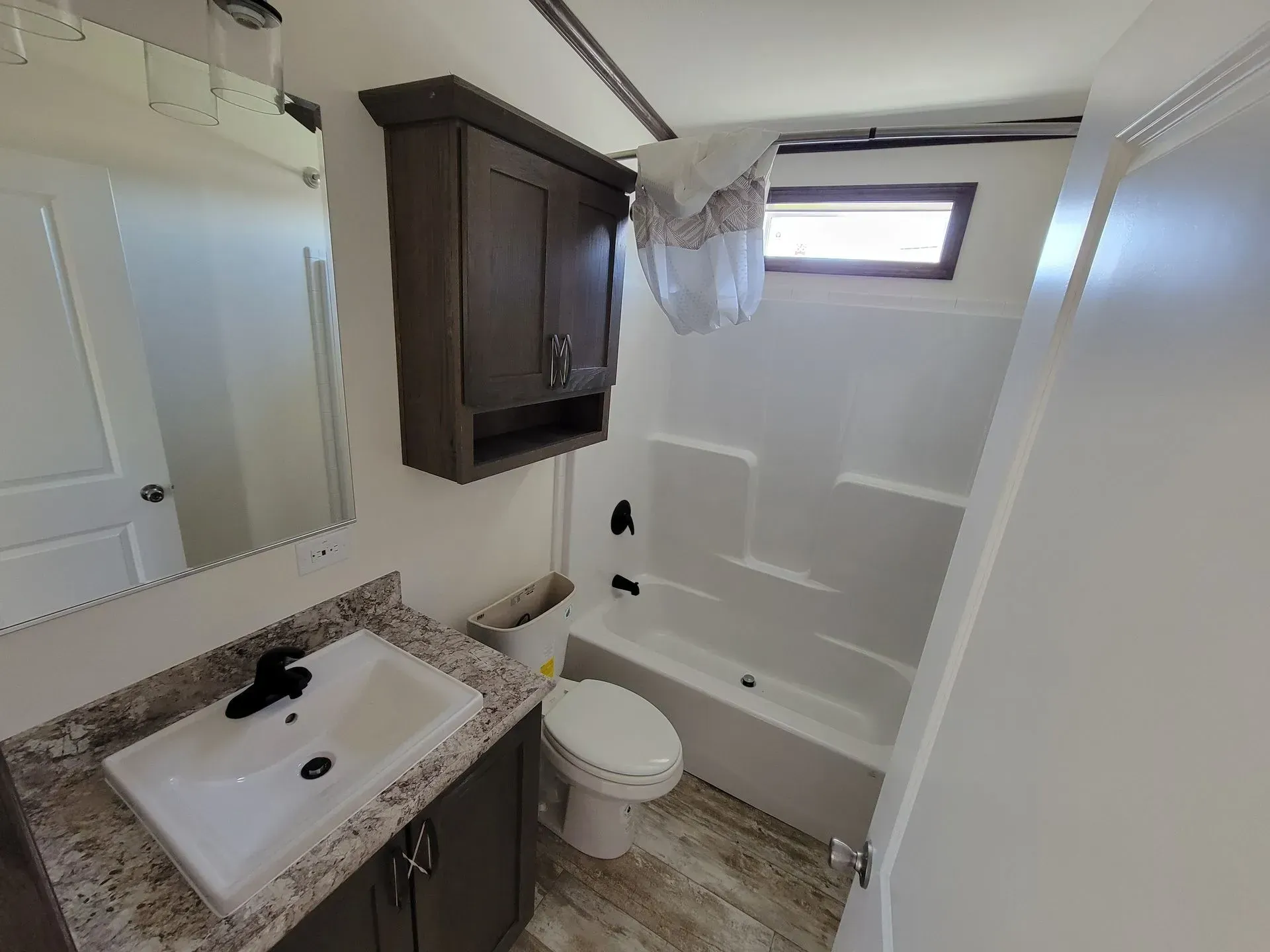 Bathroom with vanity, toilet, tub, cabinet, and small window.