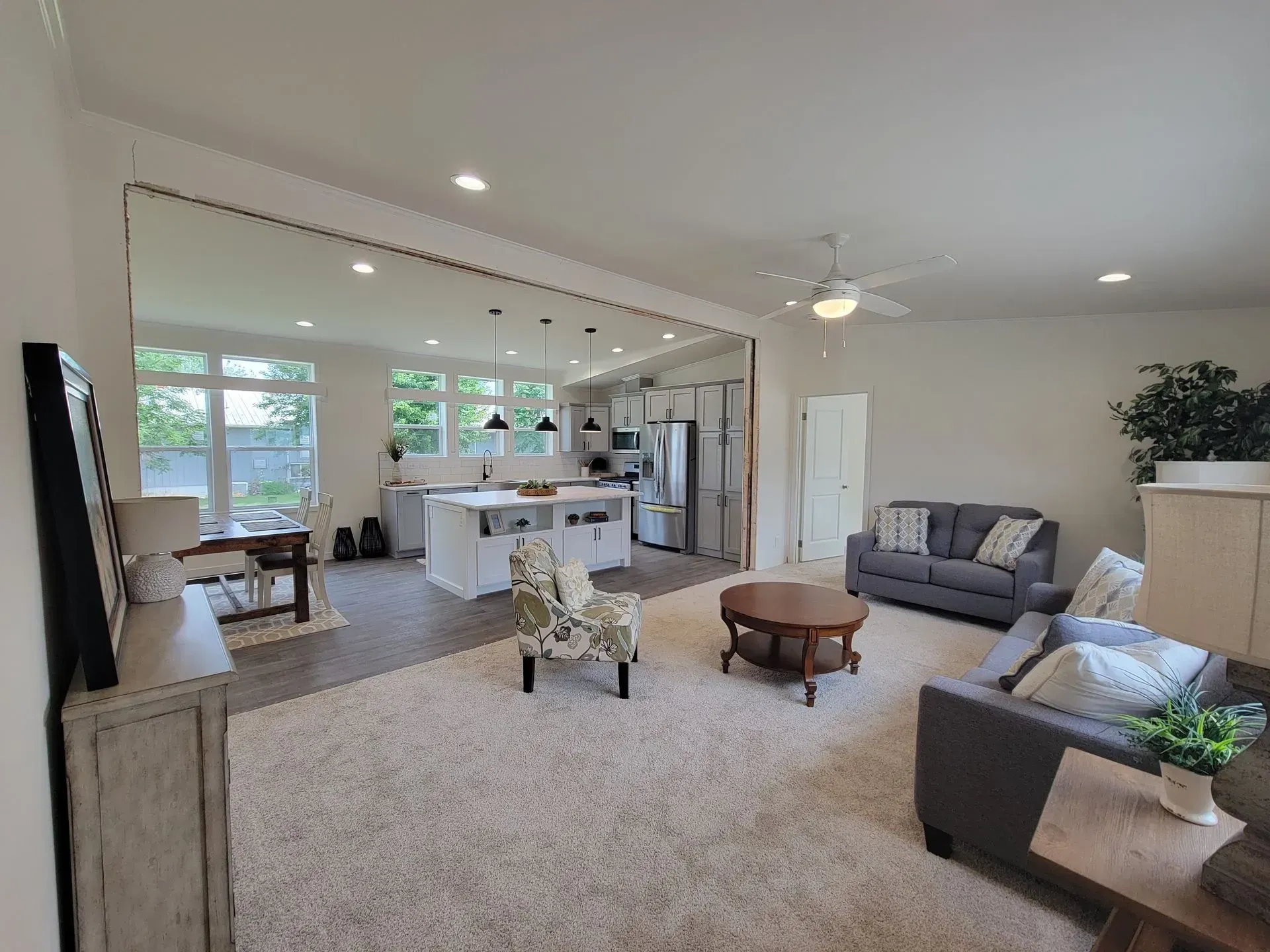 Open-concept living space with kitchen and living room visible. Neutral colors, natural light, and modern furnishings.