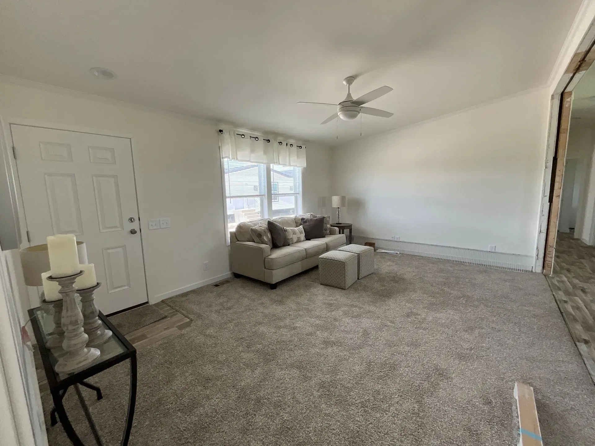 Living room with light carpet, white walls, sofa, and a ceiling fan.