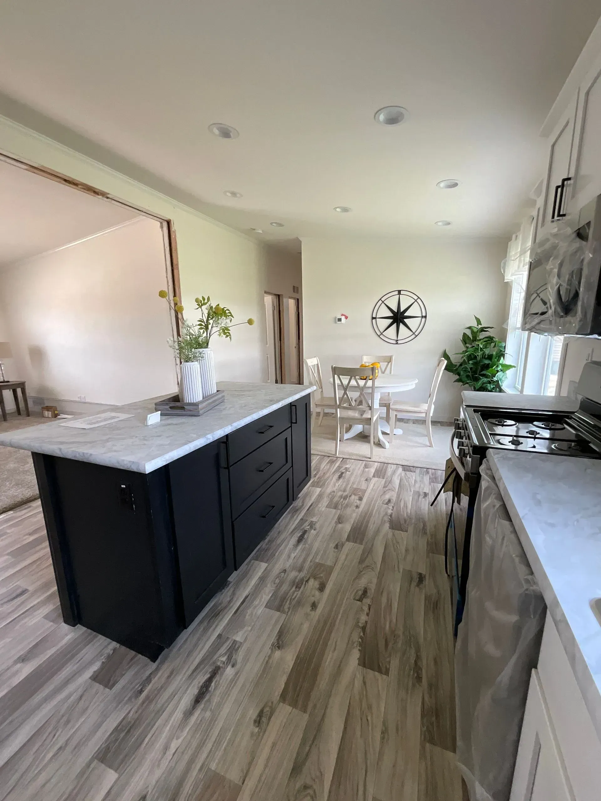 Kitchen remodel: black island with white countertop, dining area with round table, hardwood floor.