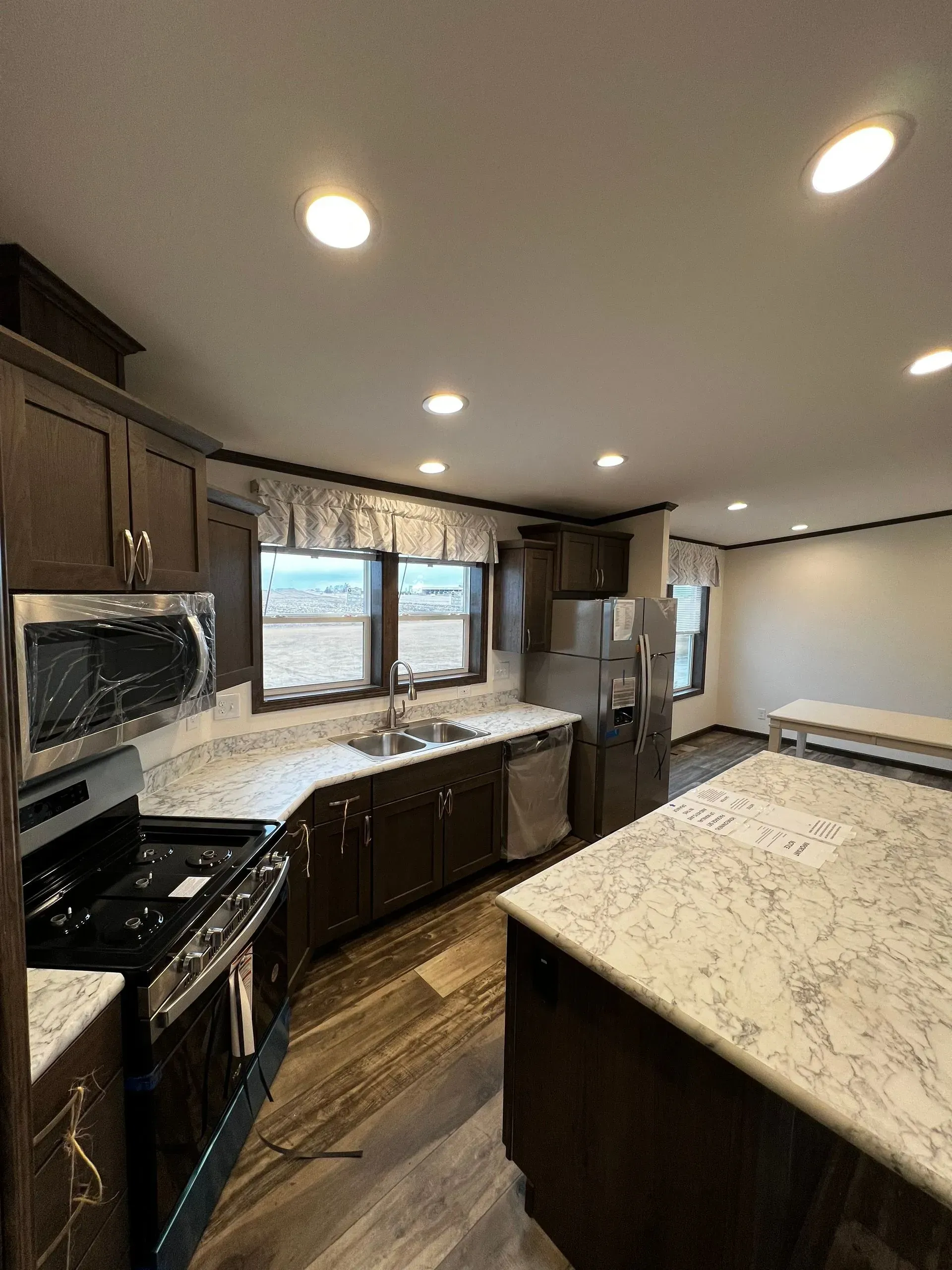 Modern kitchen with dark cabinetry, white countertops, and stainless steel appliances.