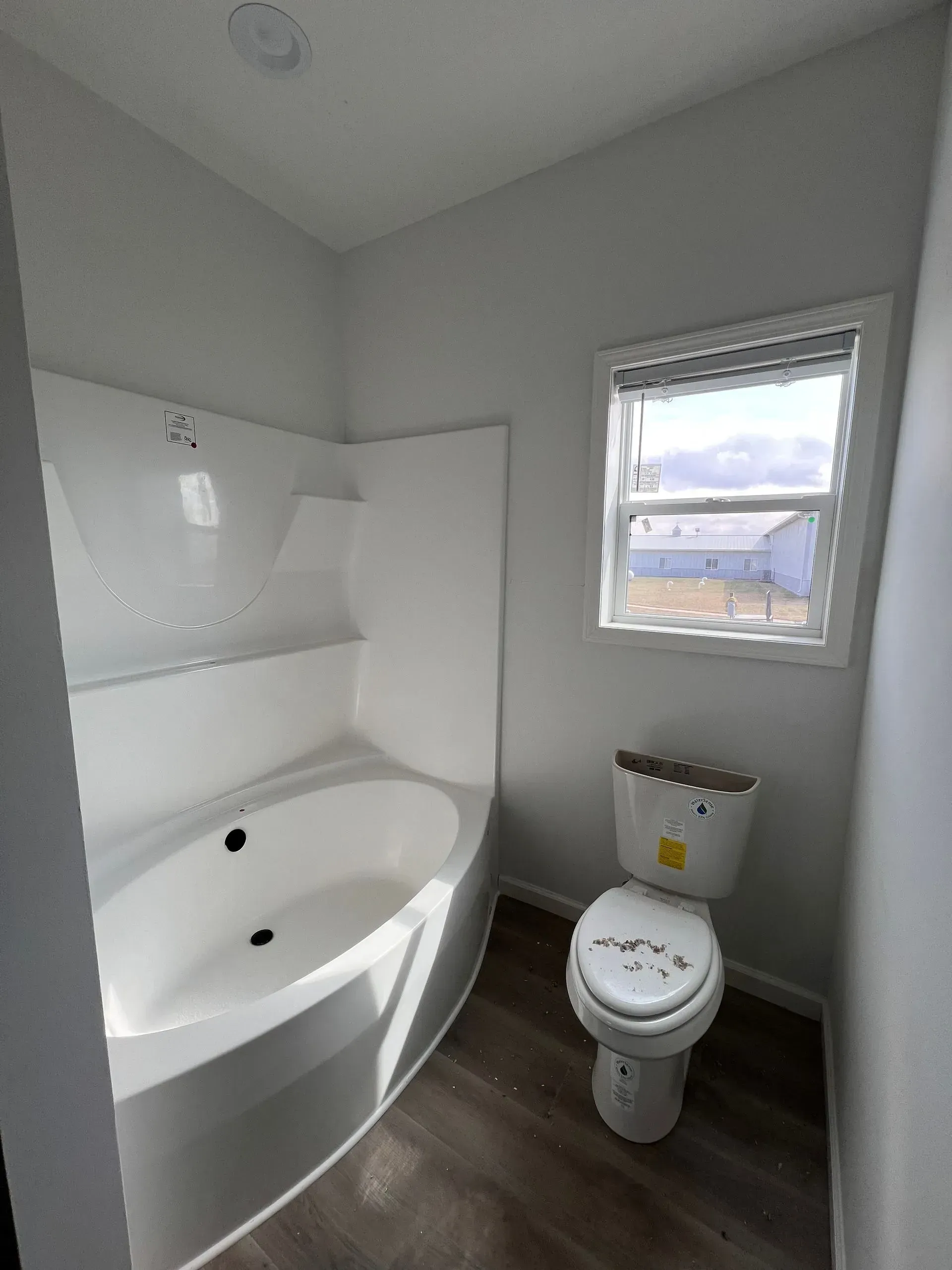 Bathroom with a bathtub, toilet, and window; gray and white color scheme.