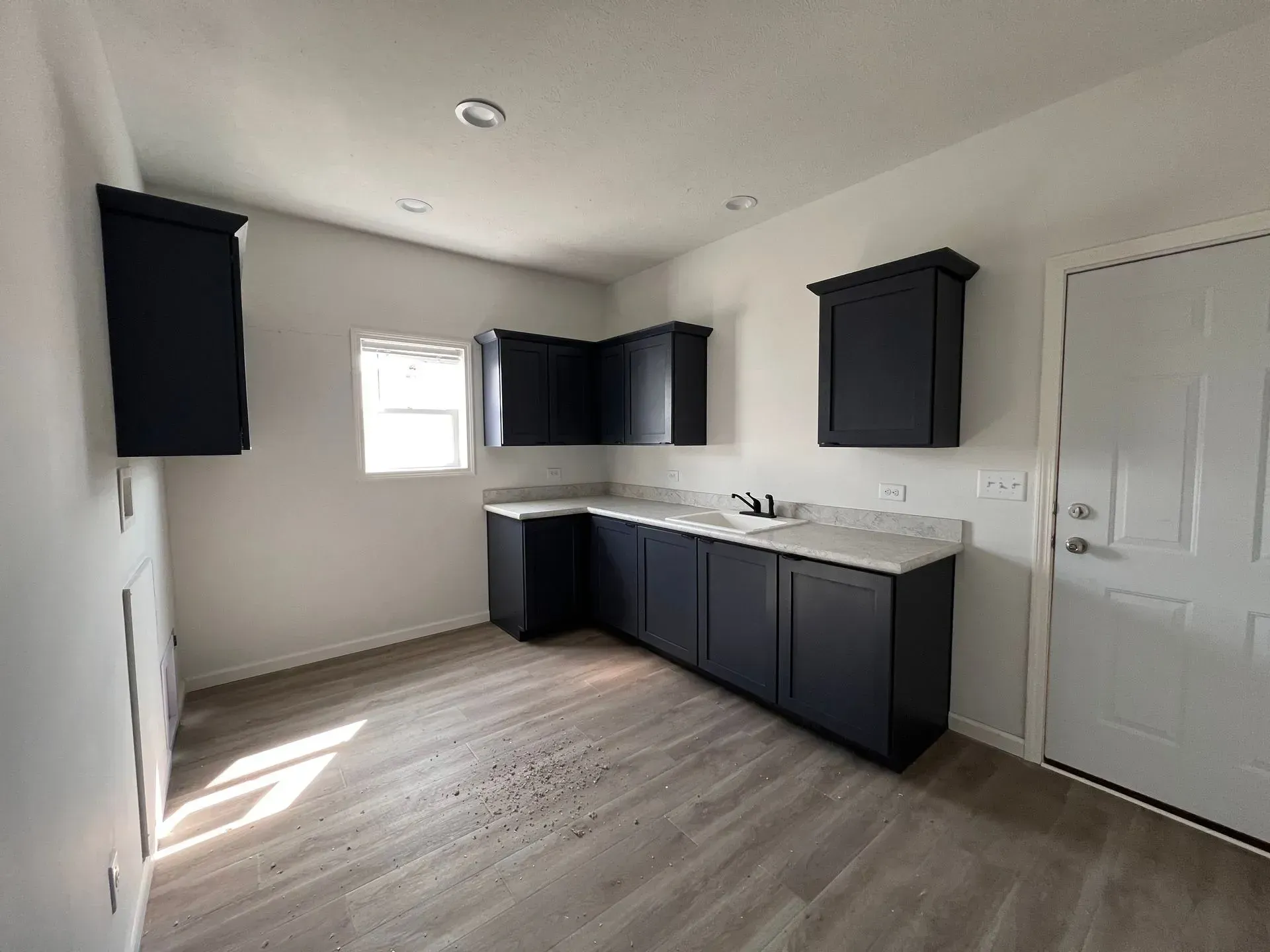 A small room with navy blue cabinets, white countertop, and white door.