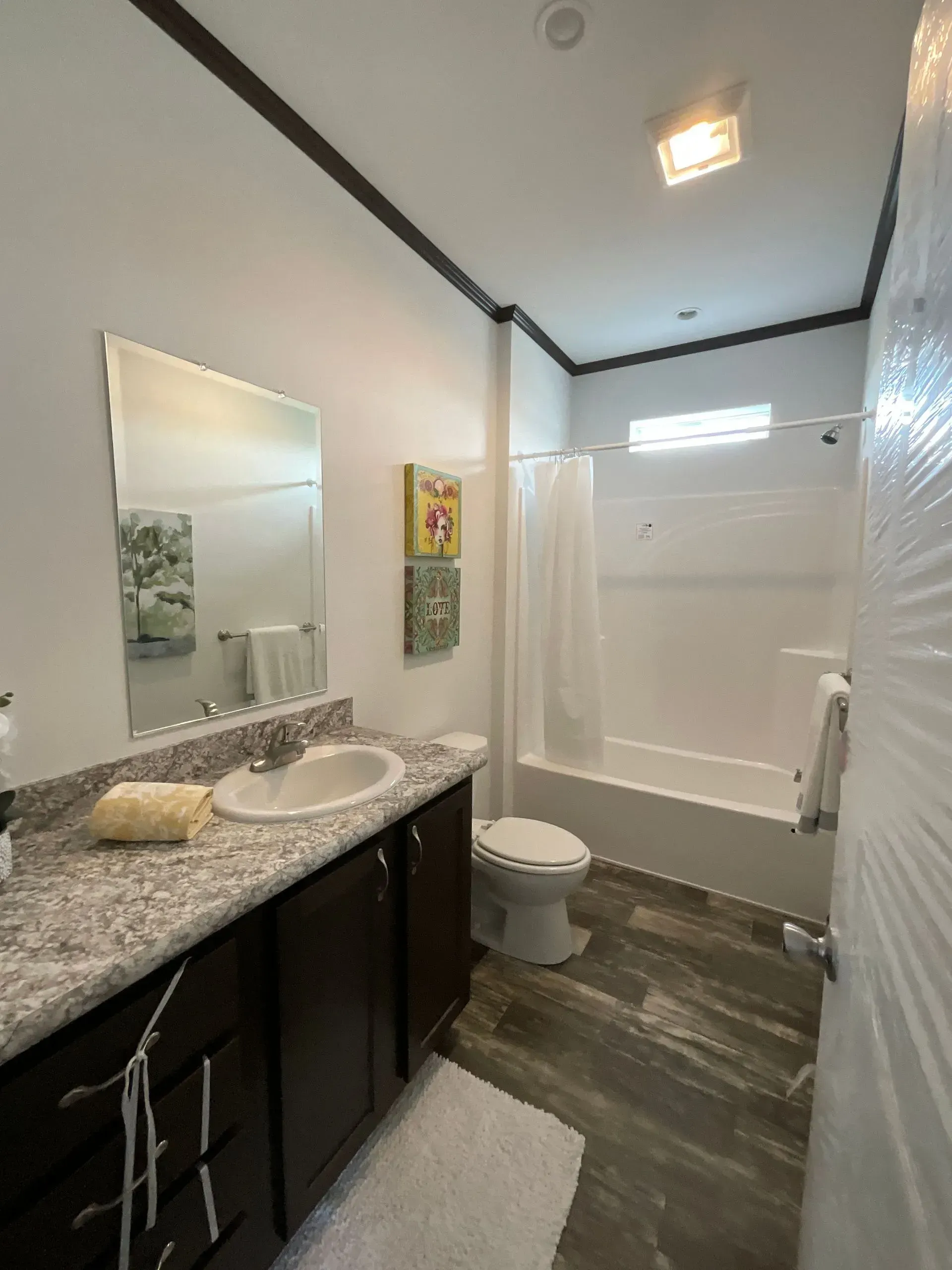 Bathroom with dark wood vanity, white toilet, and shower with curtain.