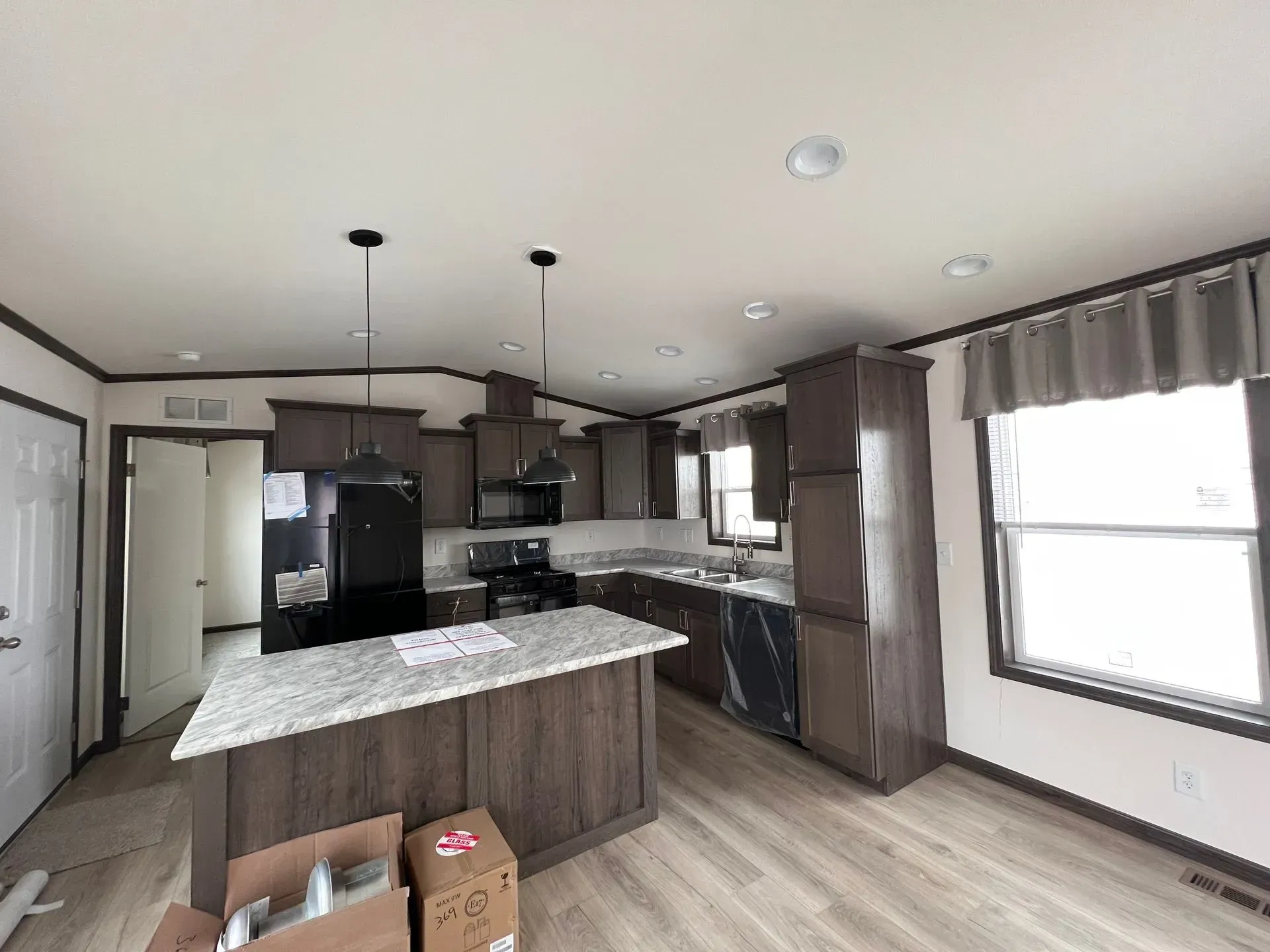 Interior view of a modern kitchen with dark brown cabinetry, granite countertops, and black appliances.