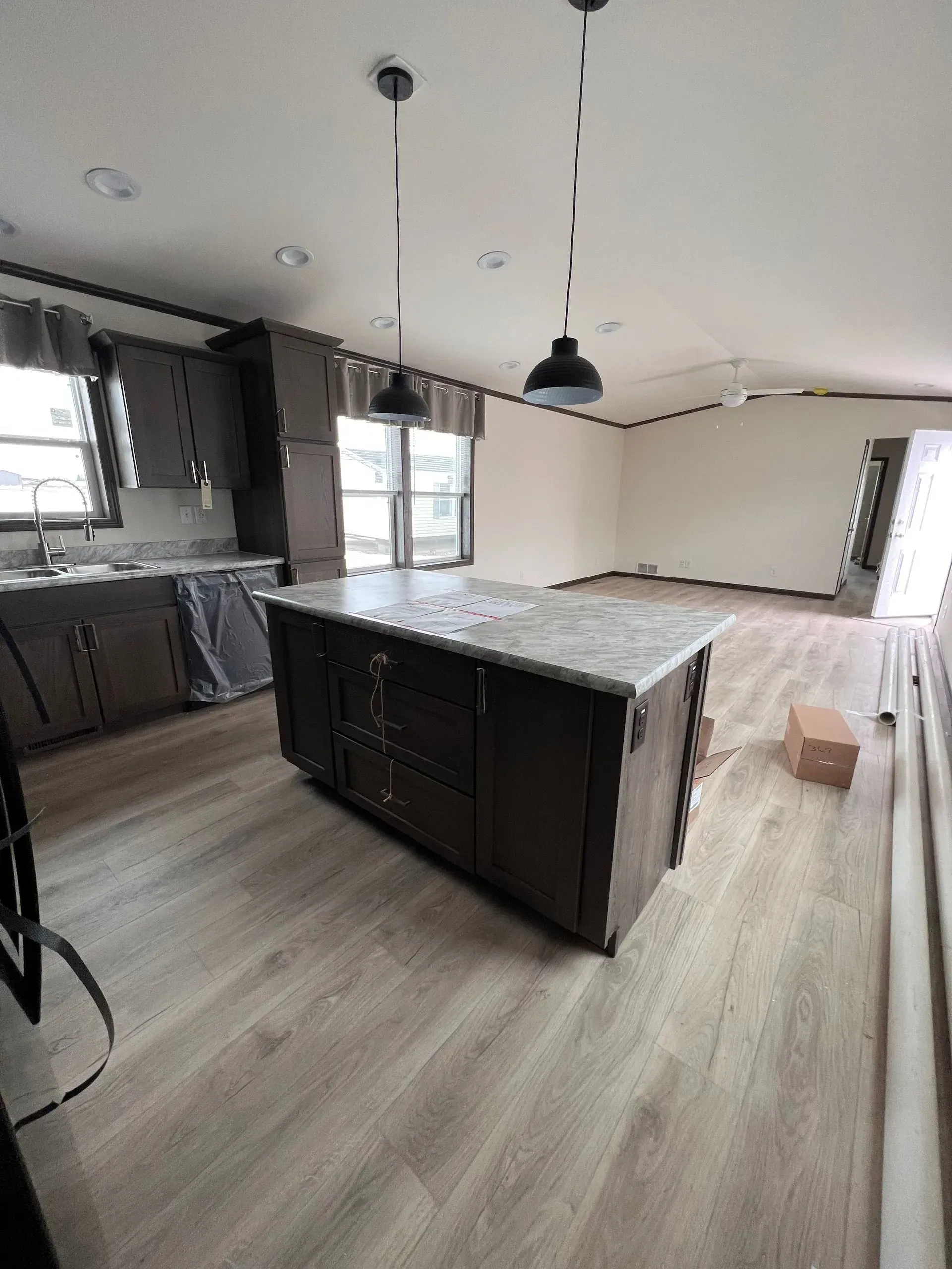 Kitchen with dark cabinets, light island, pendant lights, and light wood-look flooring.