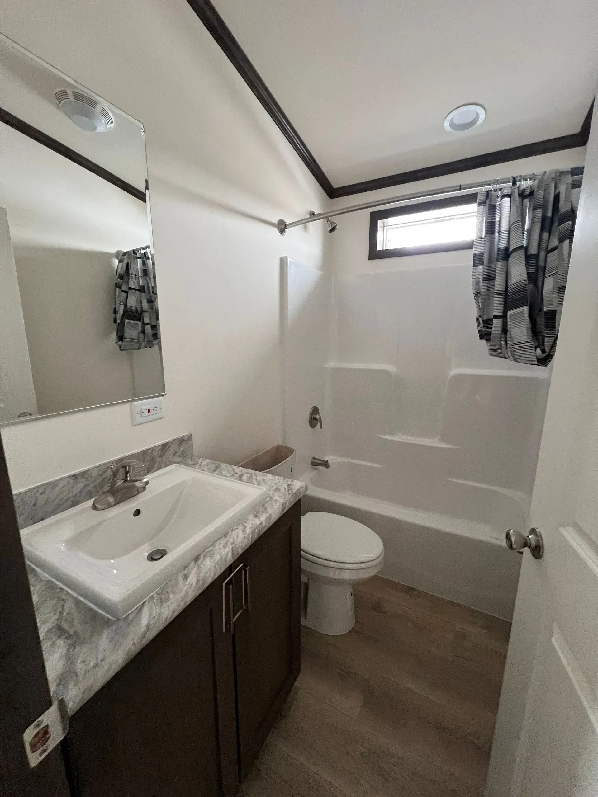 Bathroom with white walls, vanity, toilet, and shower/tub.  Brown cabinet and beige flooring.