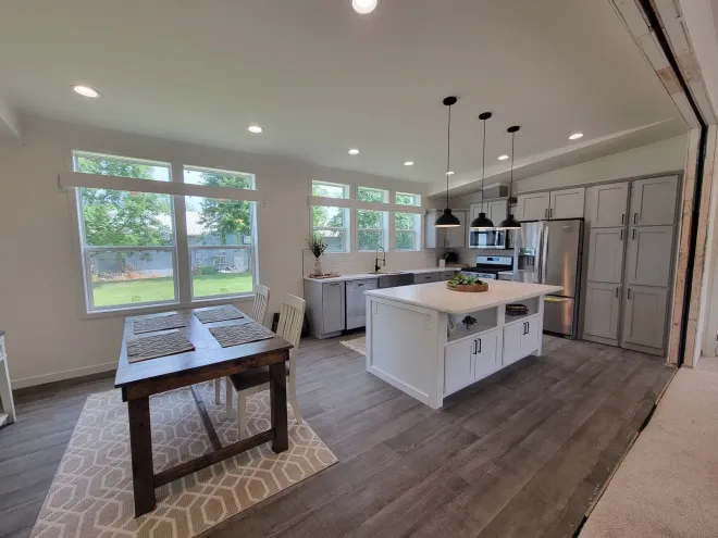 Spacious kitchen with island, stainless steel appliances, and dining table near large windows.