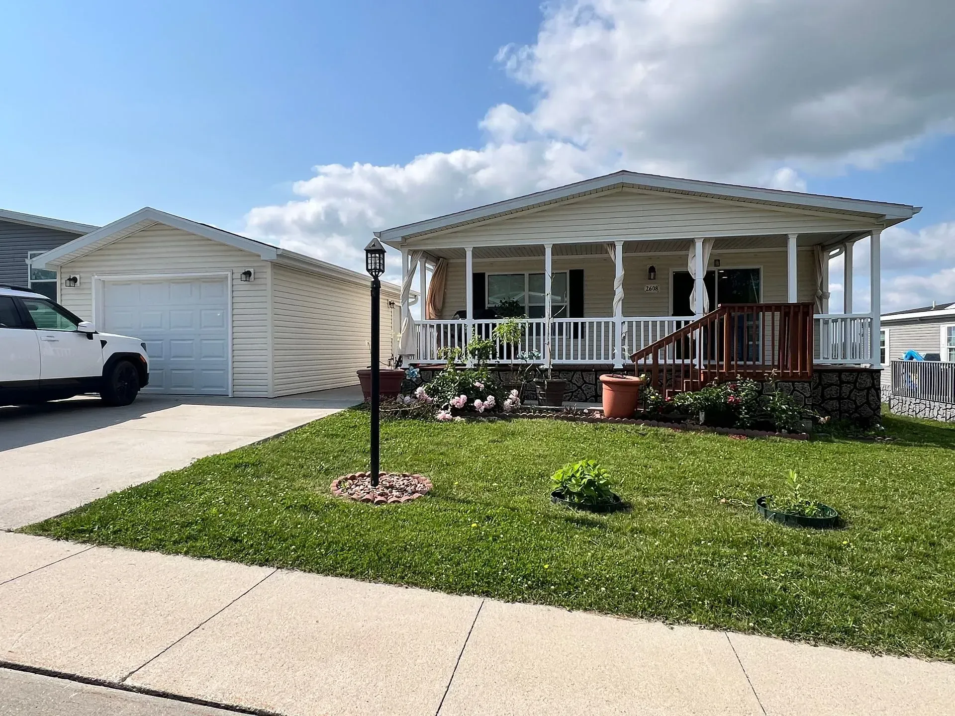 House with a covered porch and detached garage on a sunny day.