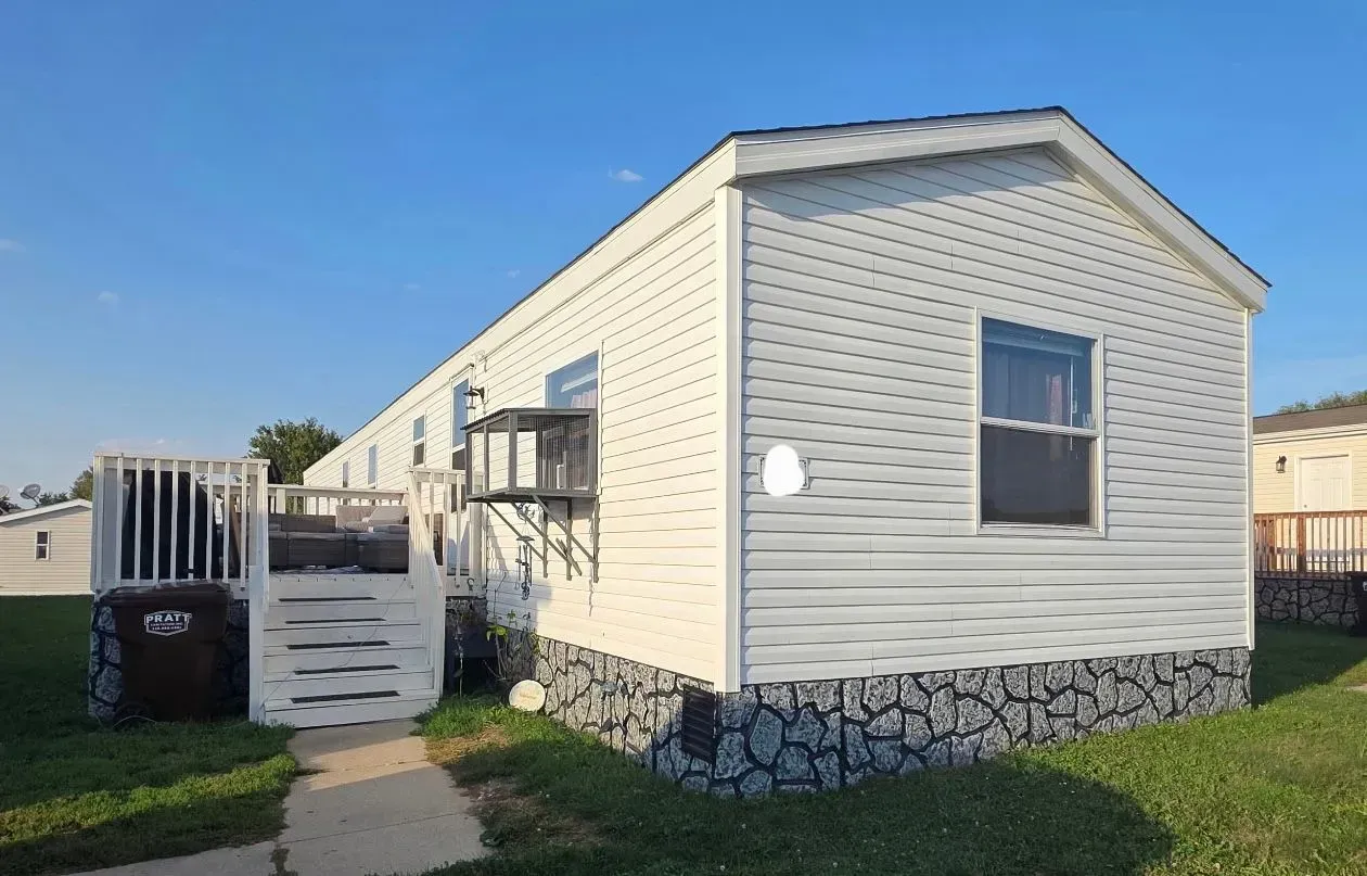 White mobile home with a small deck and blue sky.
