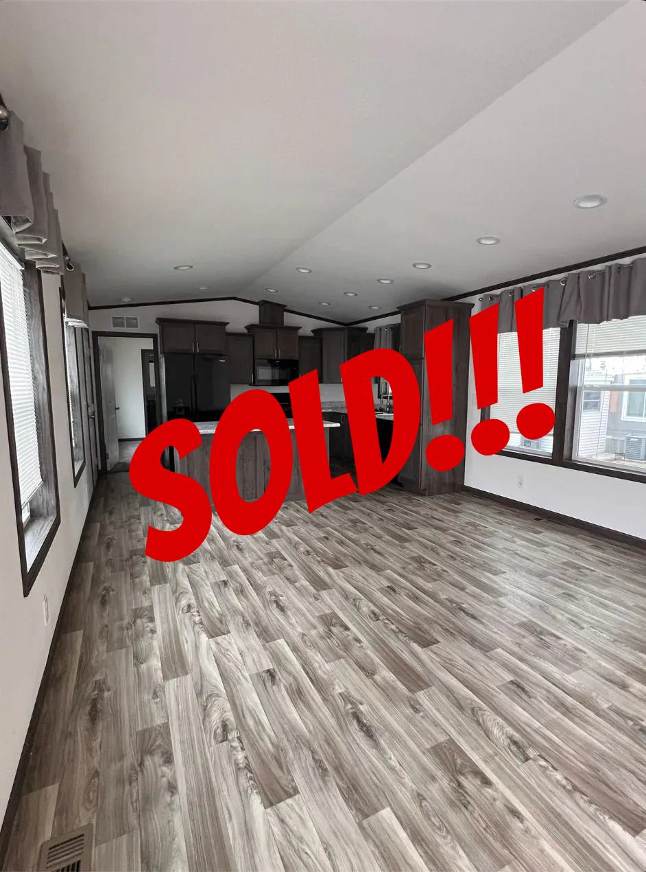 Spacious, modern interior with kitchen island, dark cabinets, and wood-look flooring.