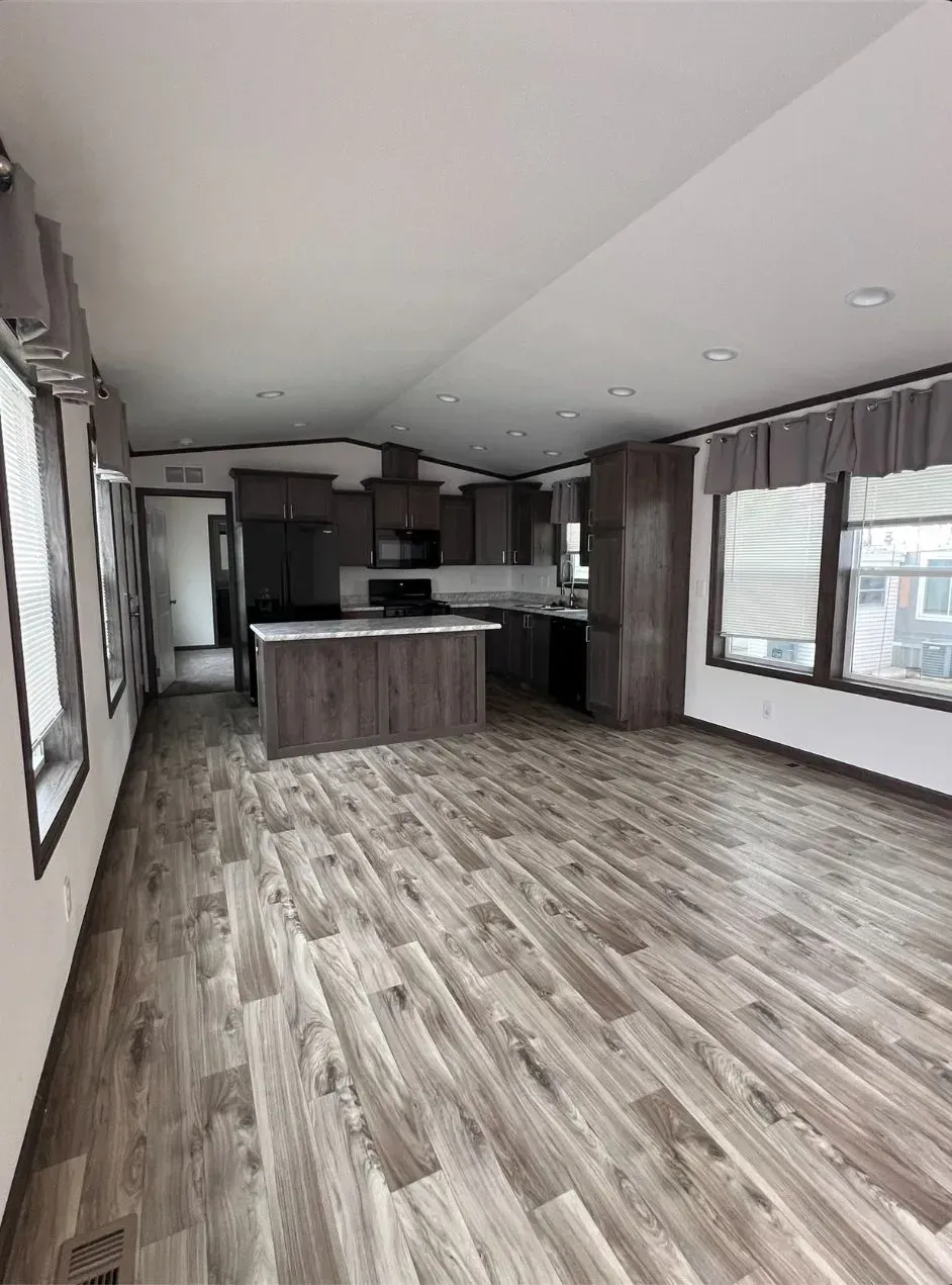 Open-concept living space with kitchen island, dark cabinets, and wood-look flooring.