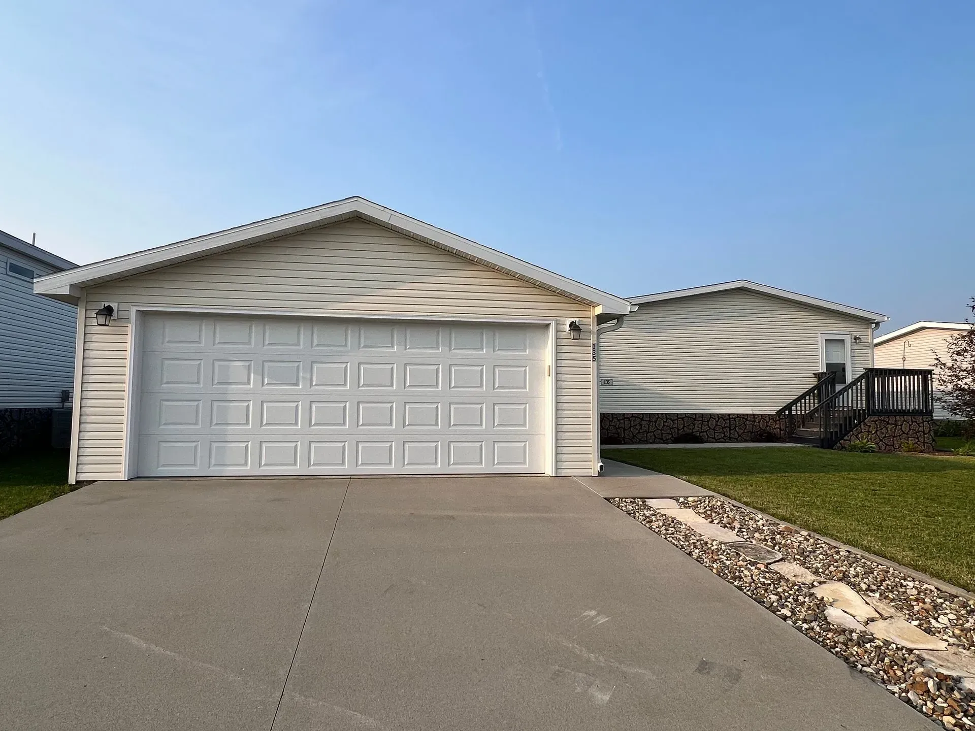 White garage attached to a house with a concrete driveway and blue sky.
