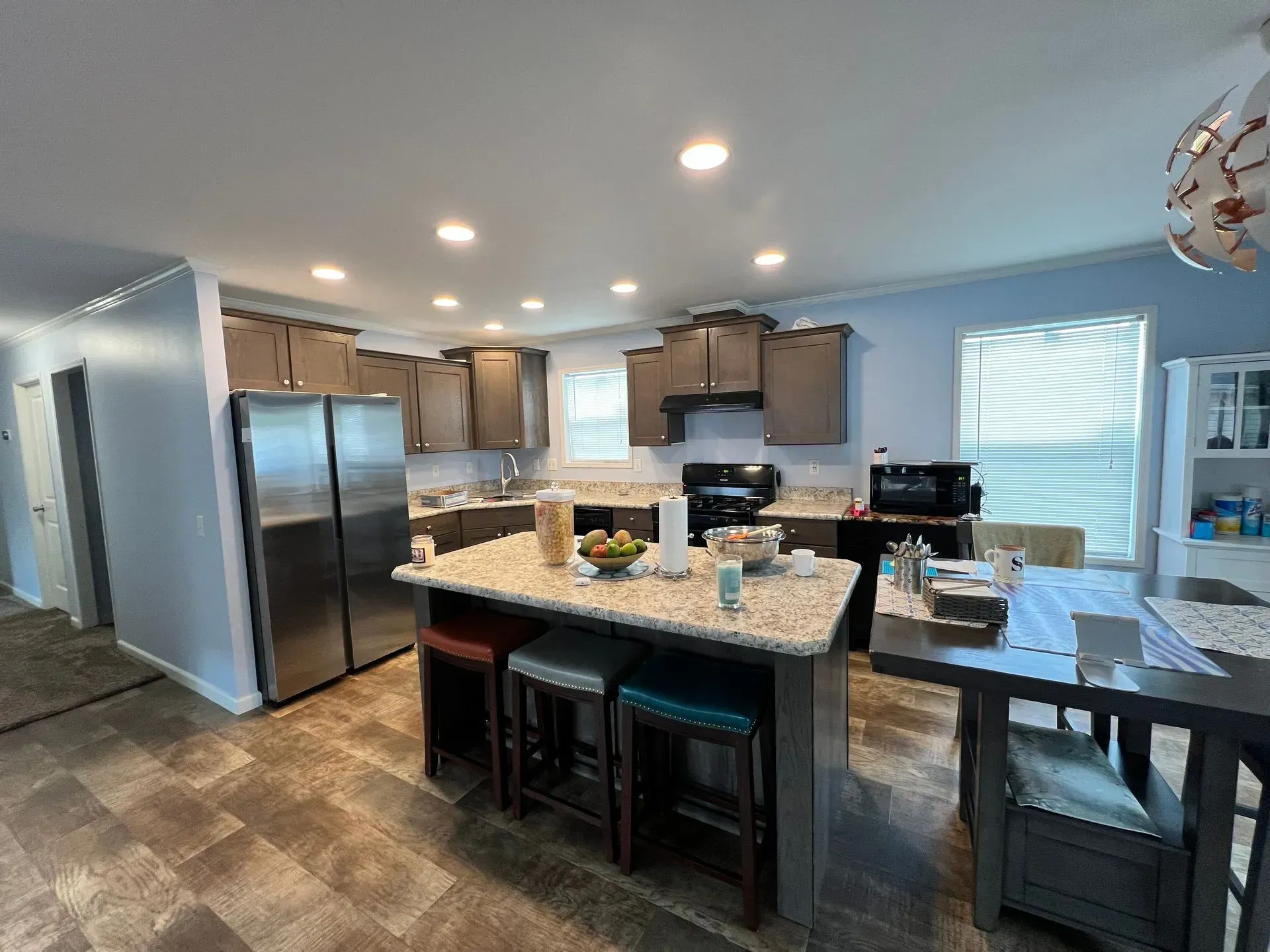 Kitchen with stainless steel appliances, an island with stools, and a dining table.