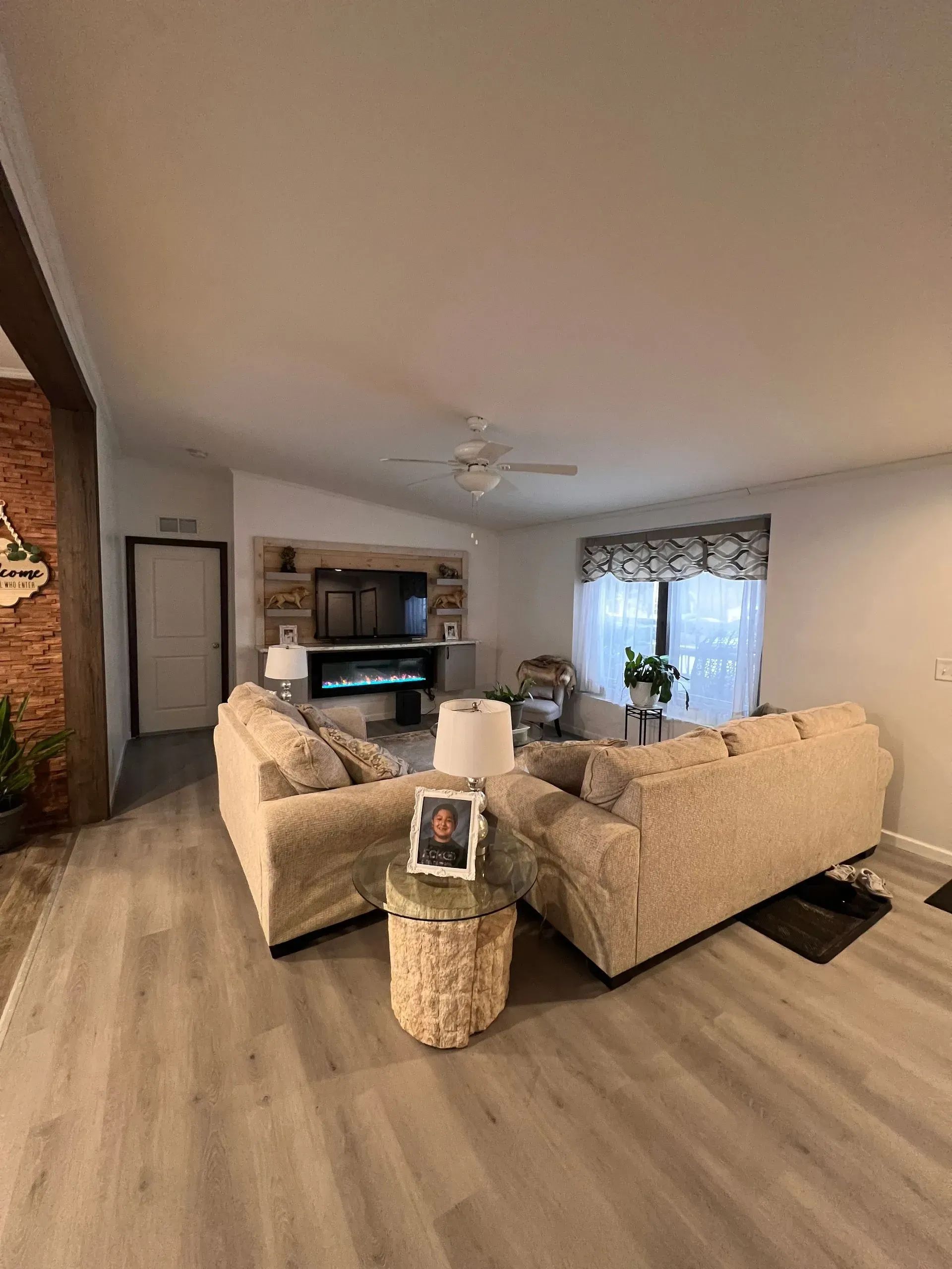 Living room with light gray flooring, two beige sofas facing a fireplace and TV.