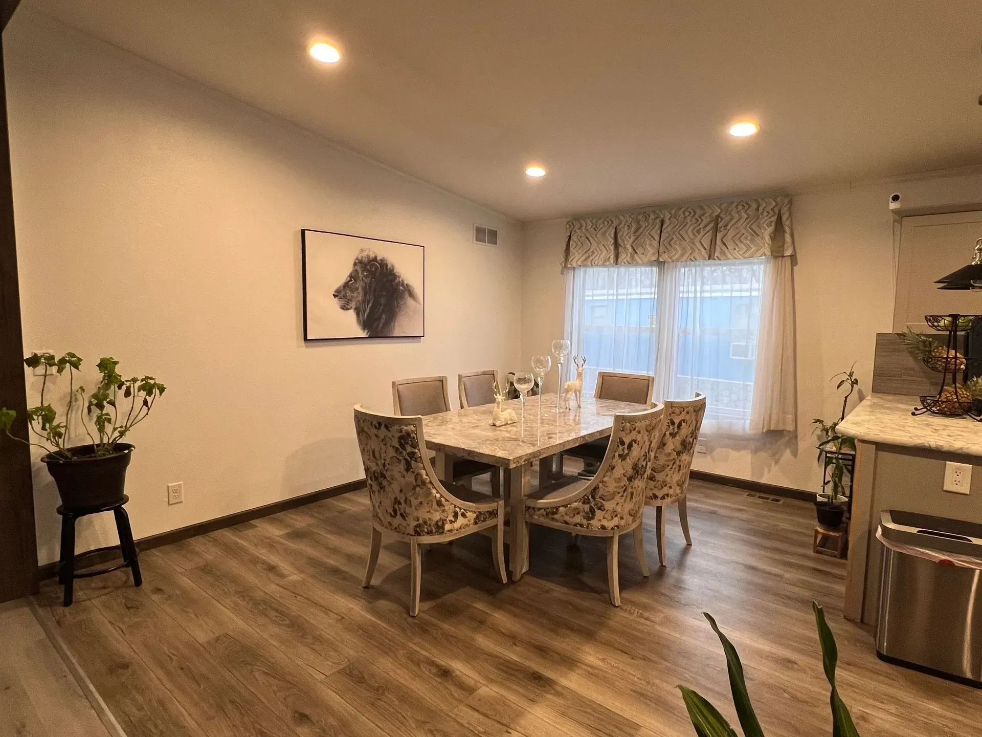 Dining room with a table, chairs, artwork, and a window with curtains.