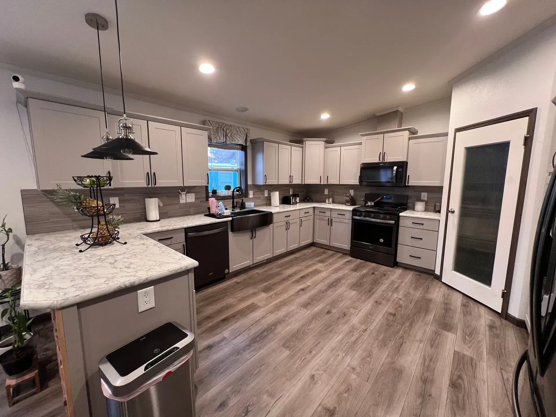 Modern kitchen with light gray cabinets, black appliances, and gray countertops.