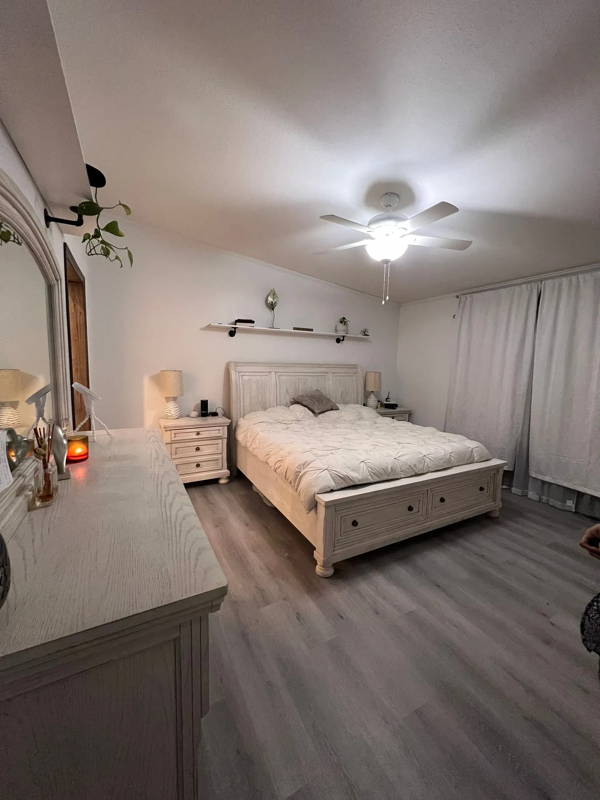Bedroom with white furniture, bed, nightstand, dresser, and curtained windows; white and gray color scheme.