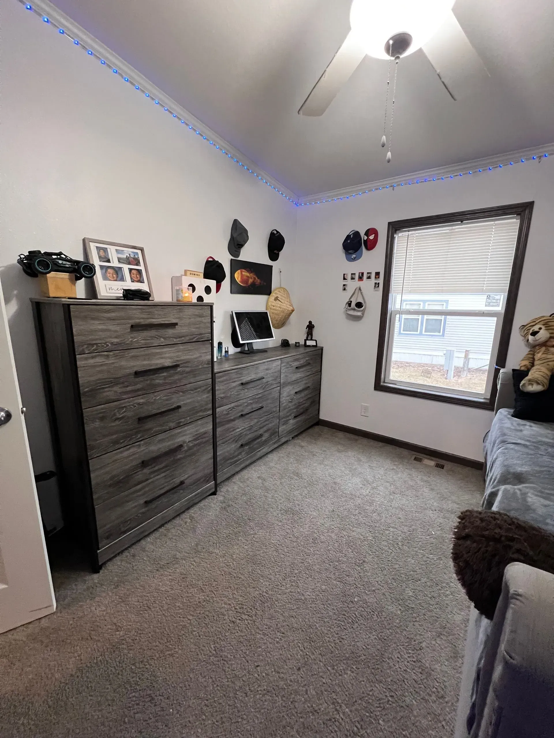 Bedroom with gray dressers, window, ceiling fan, and carpeted floor.