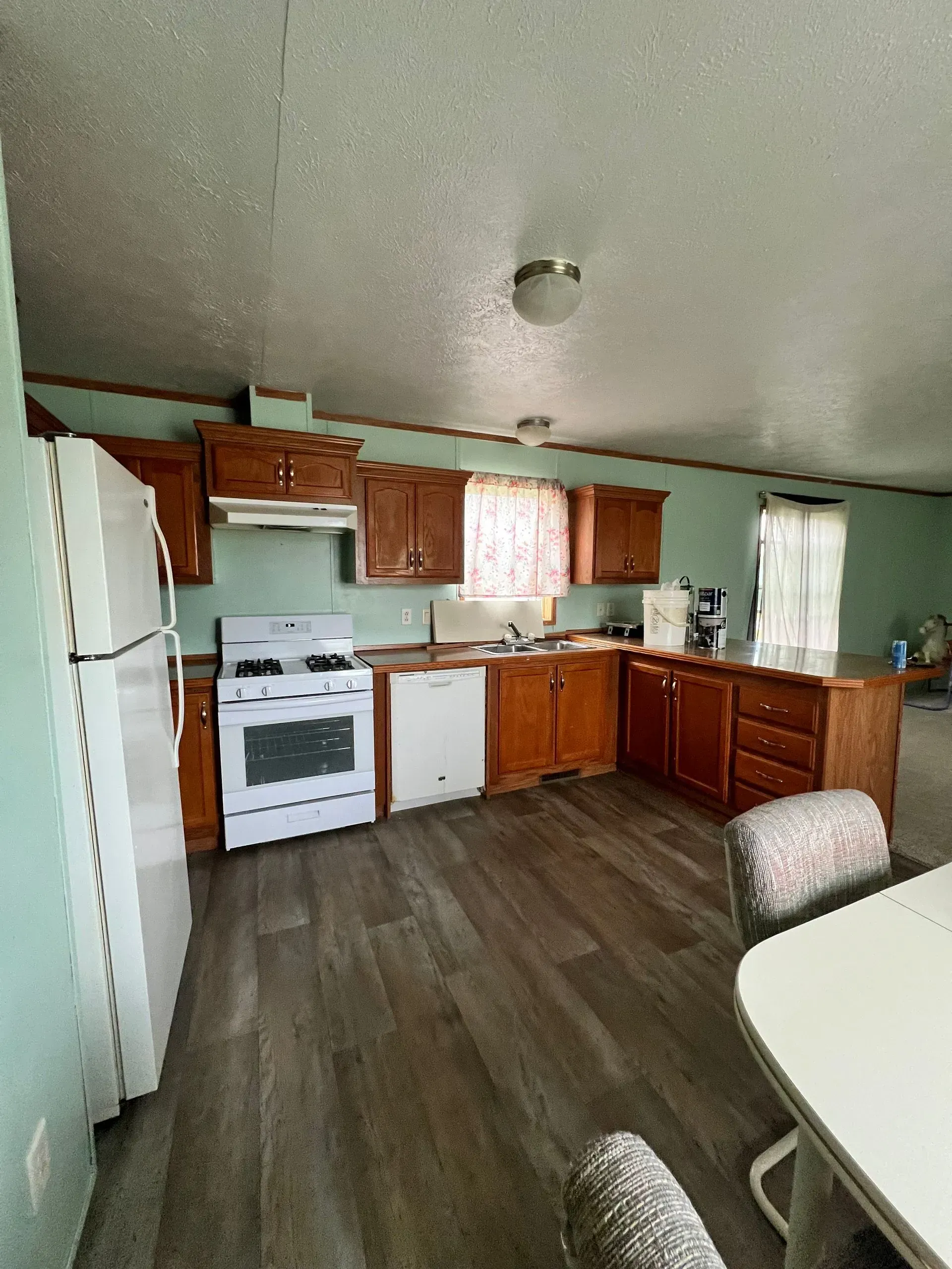 Kitchen with wooden cabinets, white appliances, and a light-colored floor.