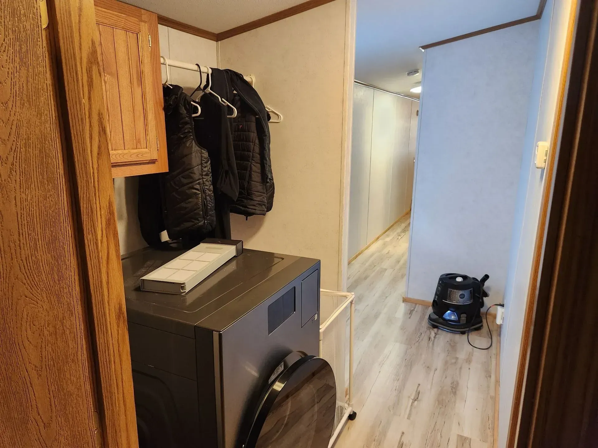 Laundry area with washer, dryer, coat rack, and hallway.