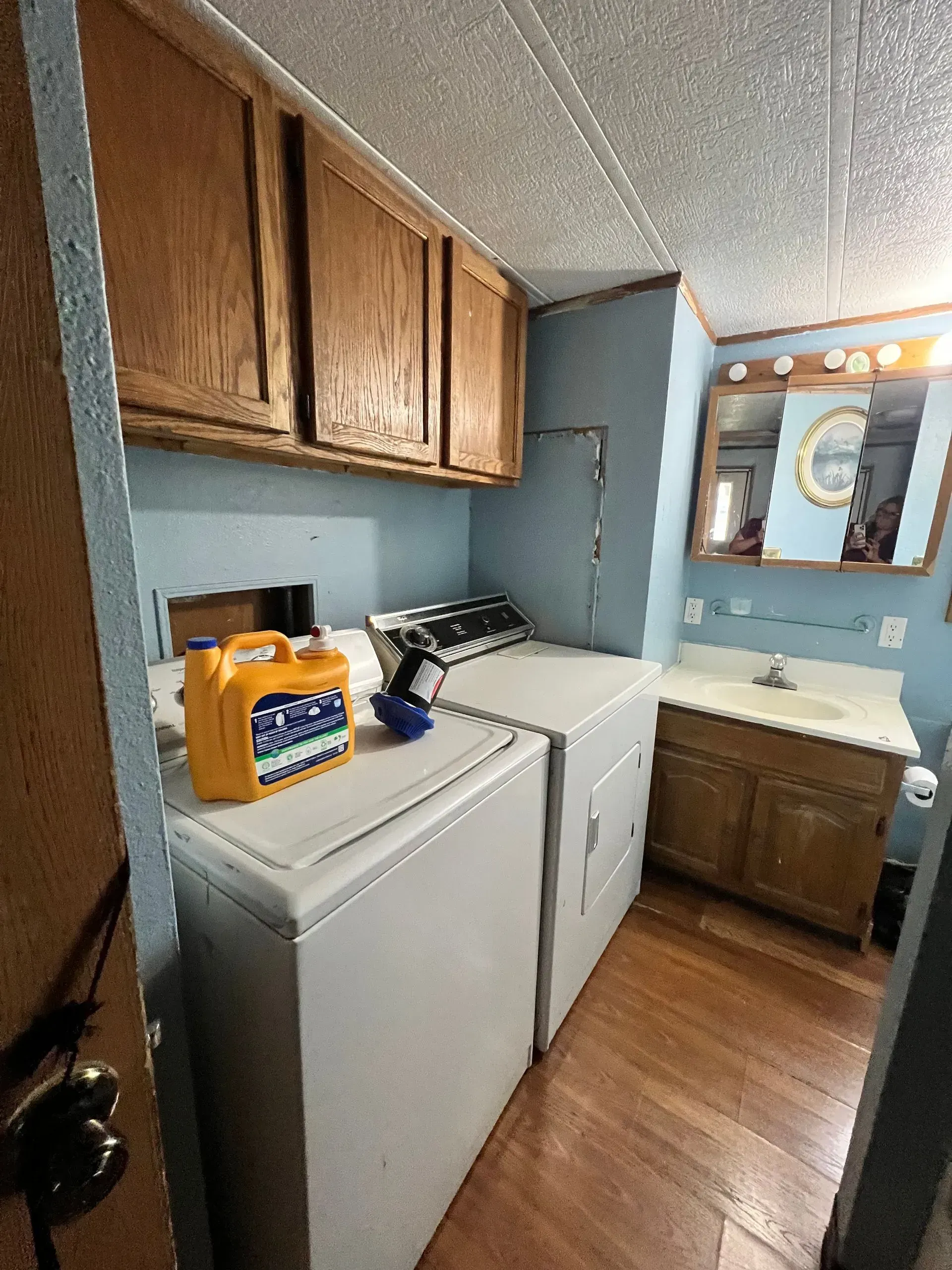 Laundry room with washer, dryer, cabinets, and a sink with mirror.