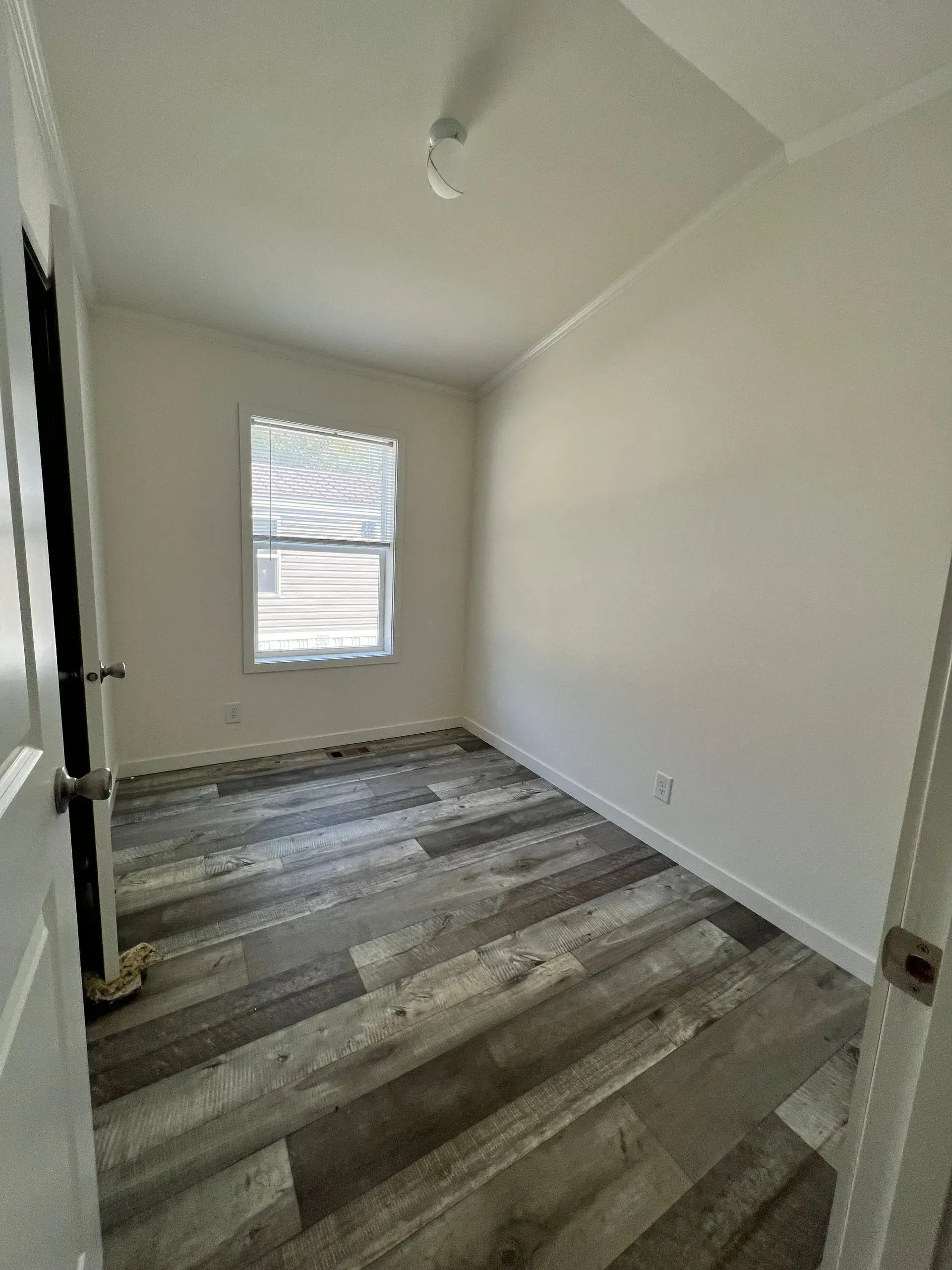 Empty room with wood-look flooring, a window, and white walls.