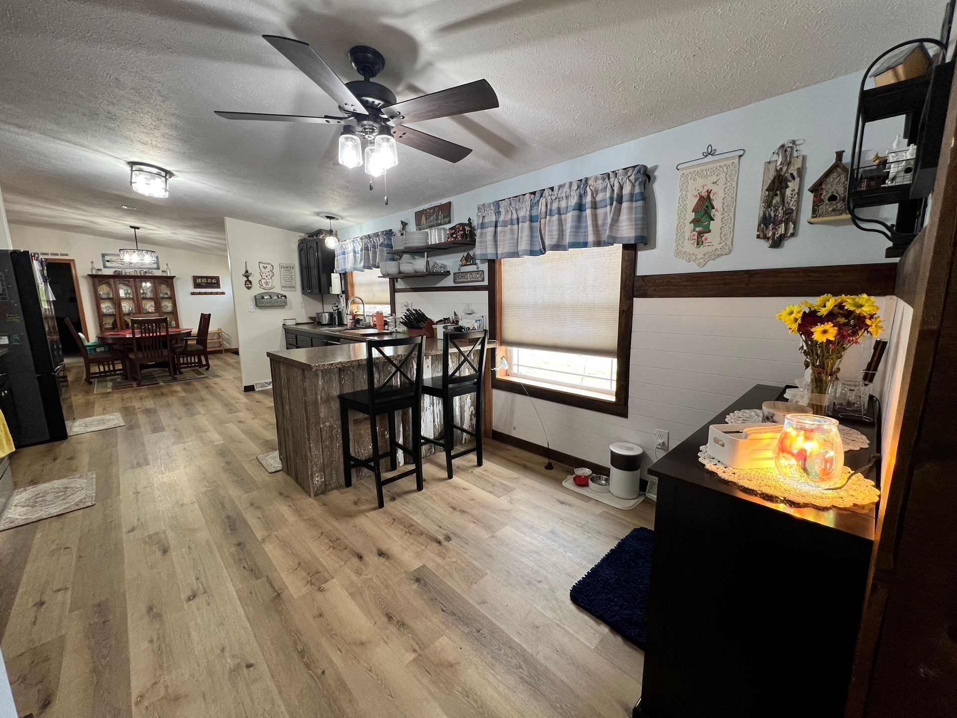 A view of a home interior featuring an open-concept kitchen with a breakfast bar, wood floors, and a dining area.