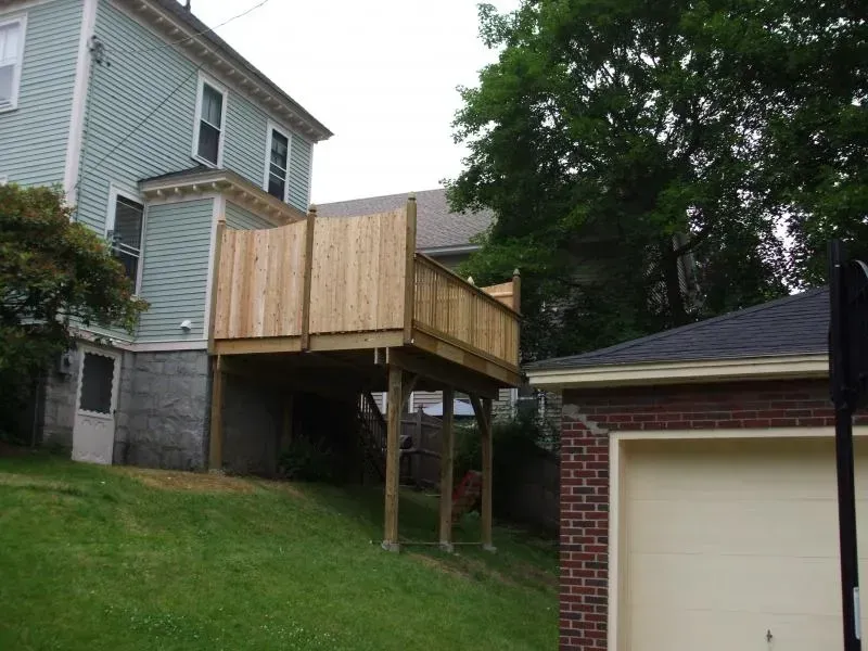 A house with a wooden deck next to a garage