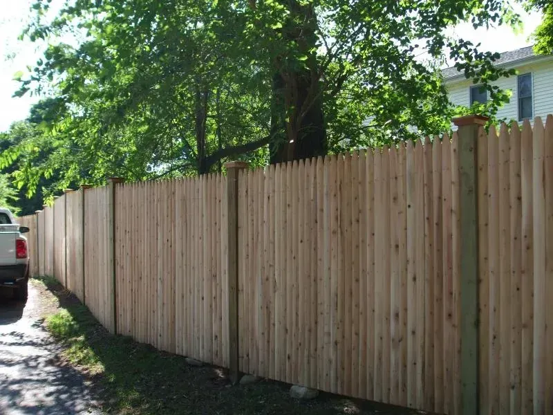 A white truck is parked next to a wooden fence