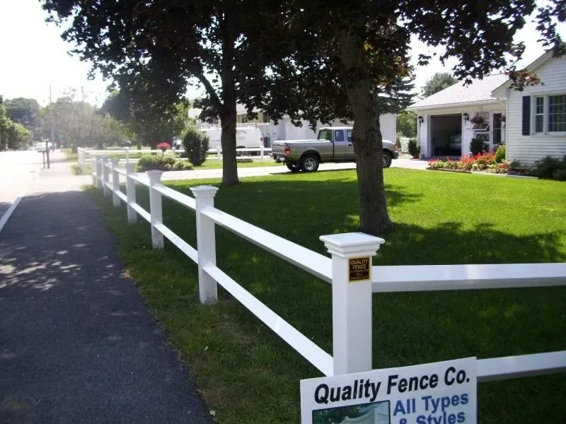 A white fence with a sign that says quality fence co.