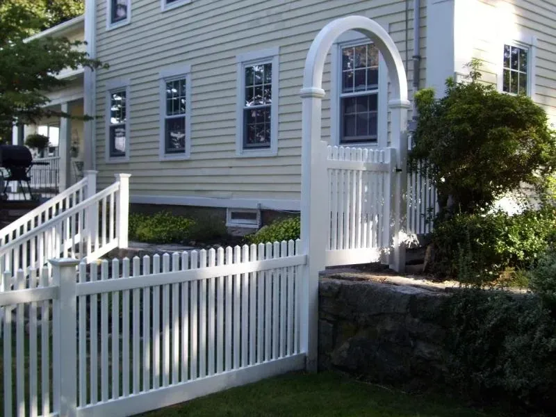 A white picket fence with a gate in front of a house