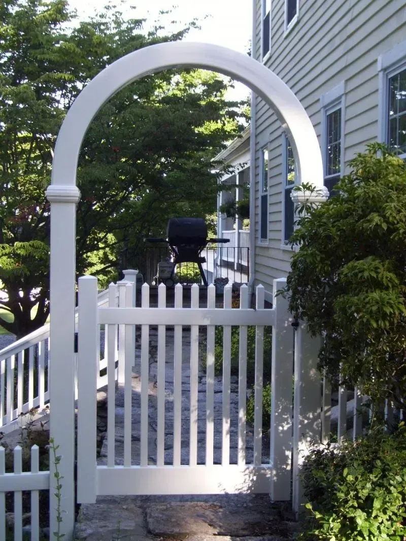 A white fence with a gate leading to a house