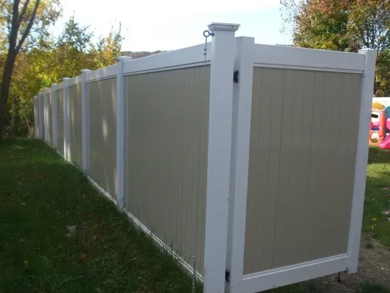 A white and tan fence with a gate in the backyard.