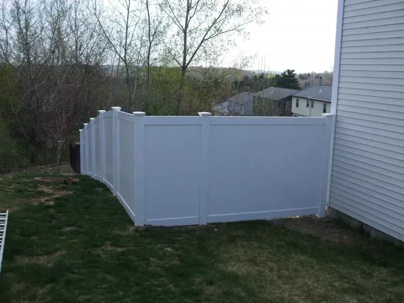 A white fence is in the backyard of a house.