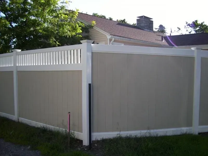 A tan and white fence with a house in the background