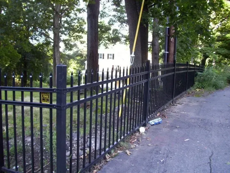 A black fence with a yellow warning sign on it