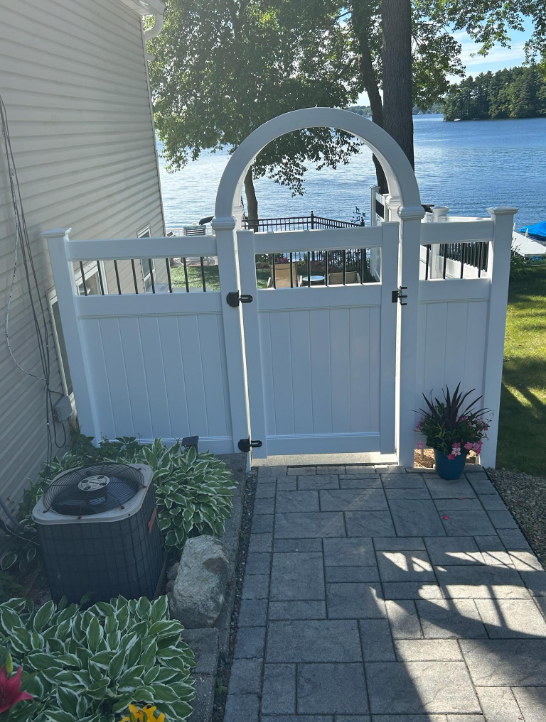 White fenced gate with archway leading to lake.