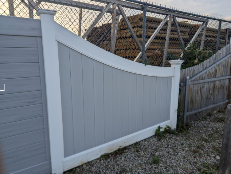 Gray and white vinyl fence with a curved top and a section of another fence.