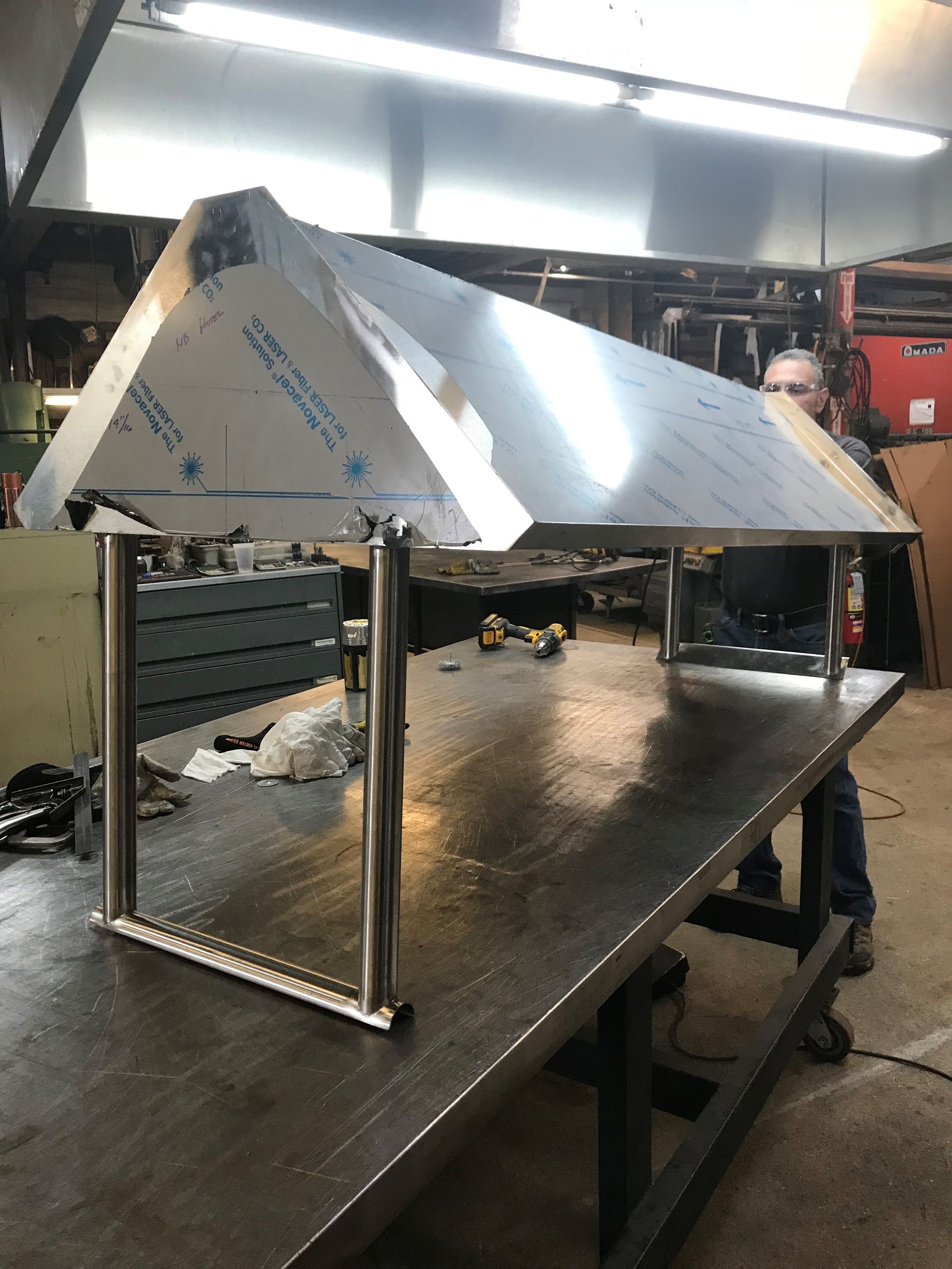 A man is sitting at a table with a stainless steel canopy over it.