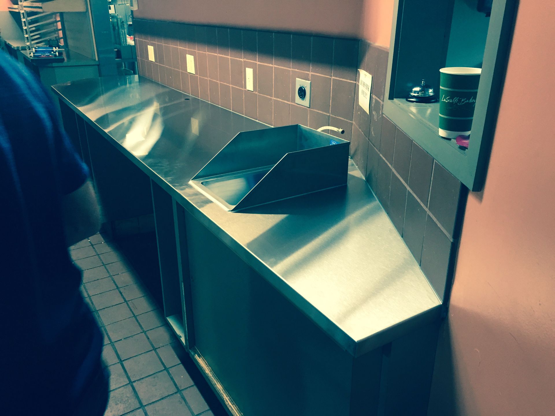 A person standing in a kitchen with a stainless steel counter top