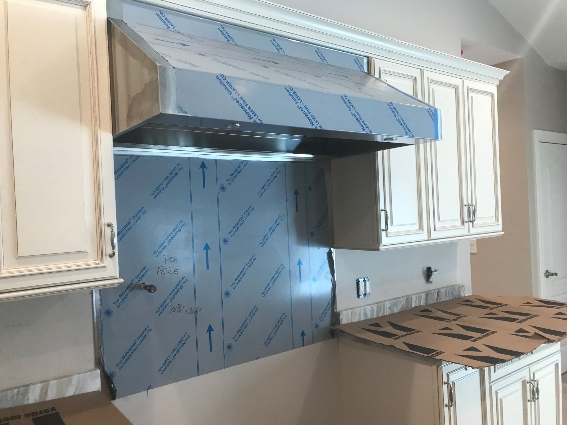 A kitchen with white cabinets and a stainless steel hood.