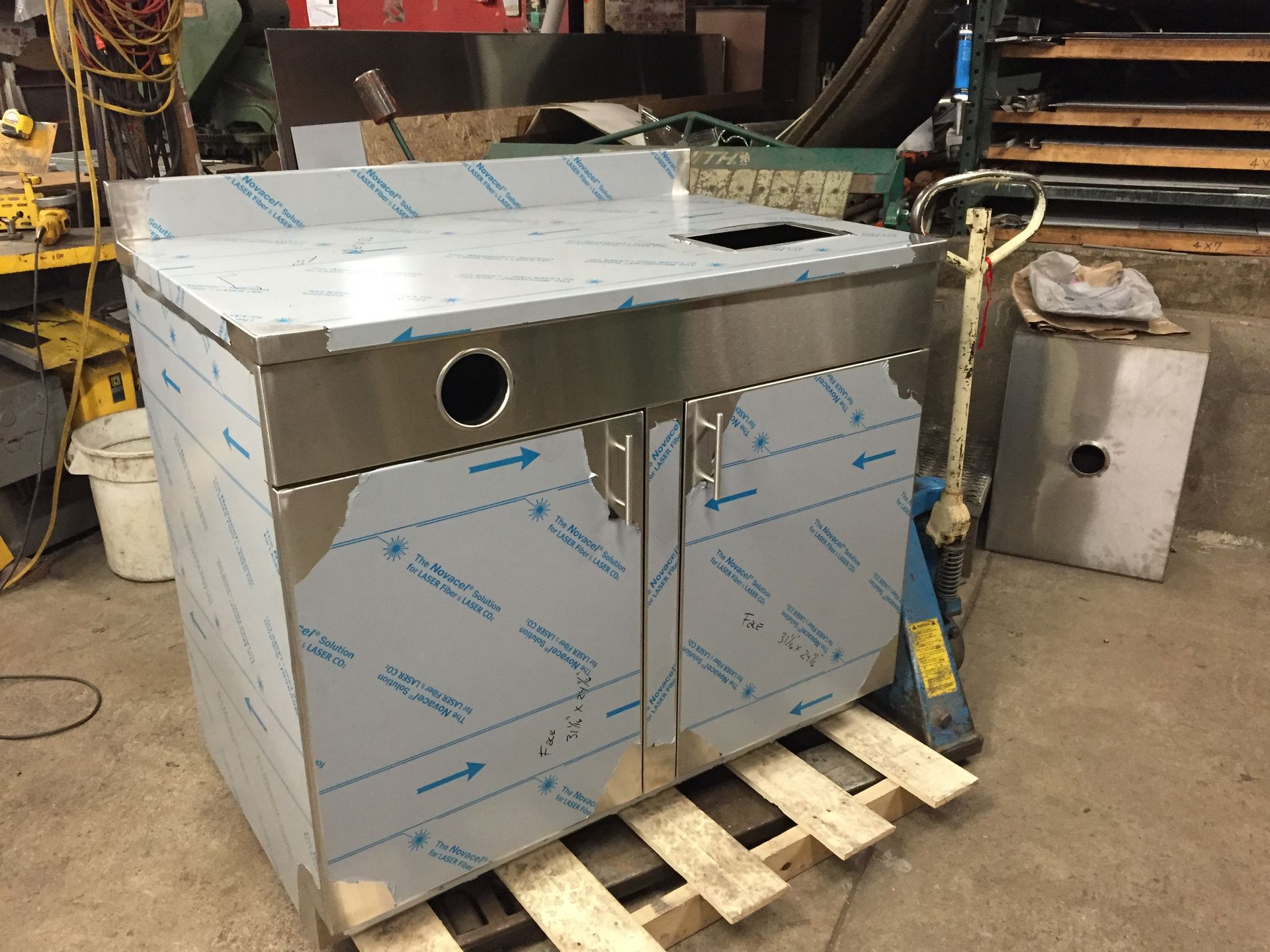 A stainless steel cabinet is sitting on a wooden pallet.