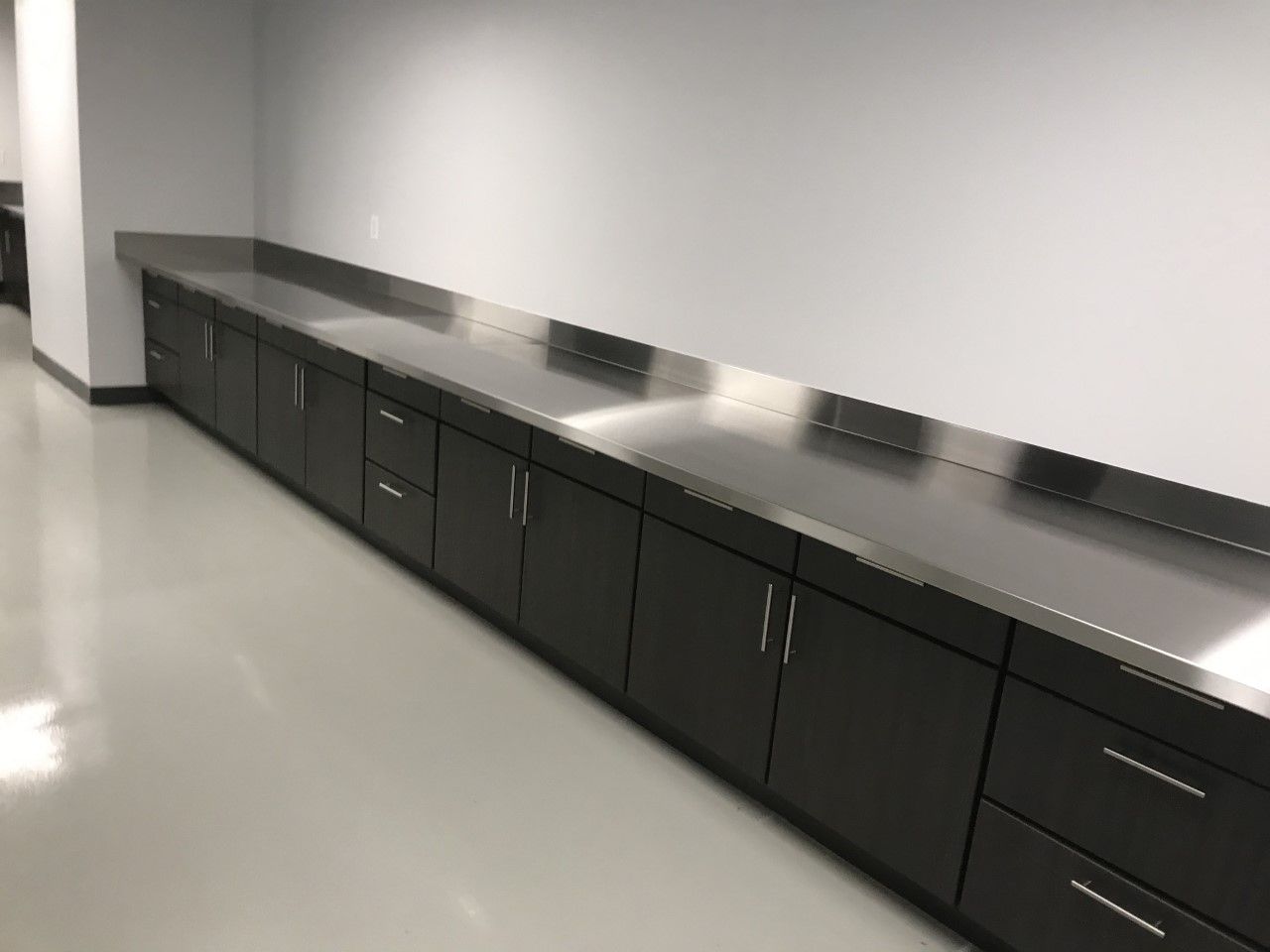 A kitchen with stainless steel counter tops and black cabinets