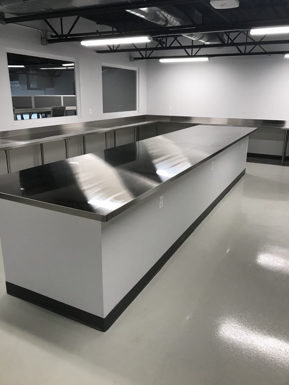 A long stainless steel counter in a kitchen with white walls