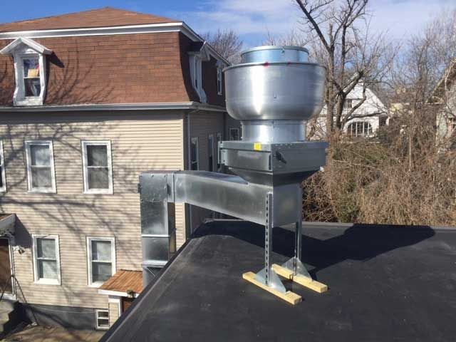 A roof with a fan on it and a house in the background