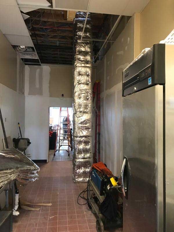 A room with a refrigerator and a ladder in it.