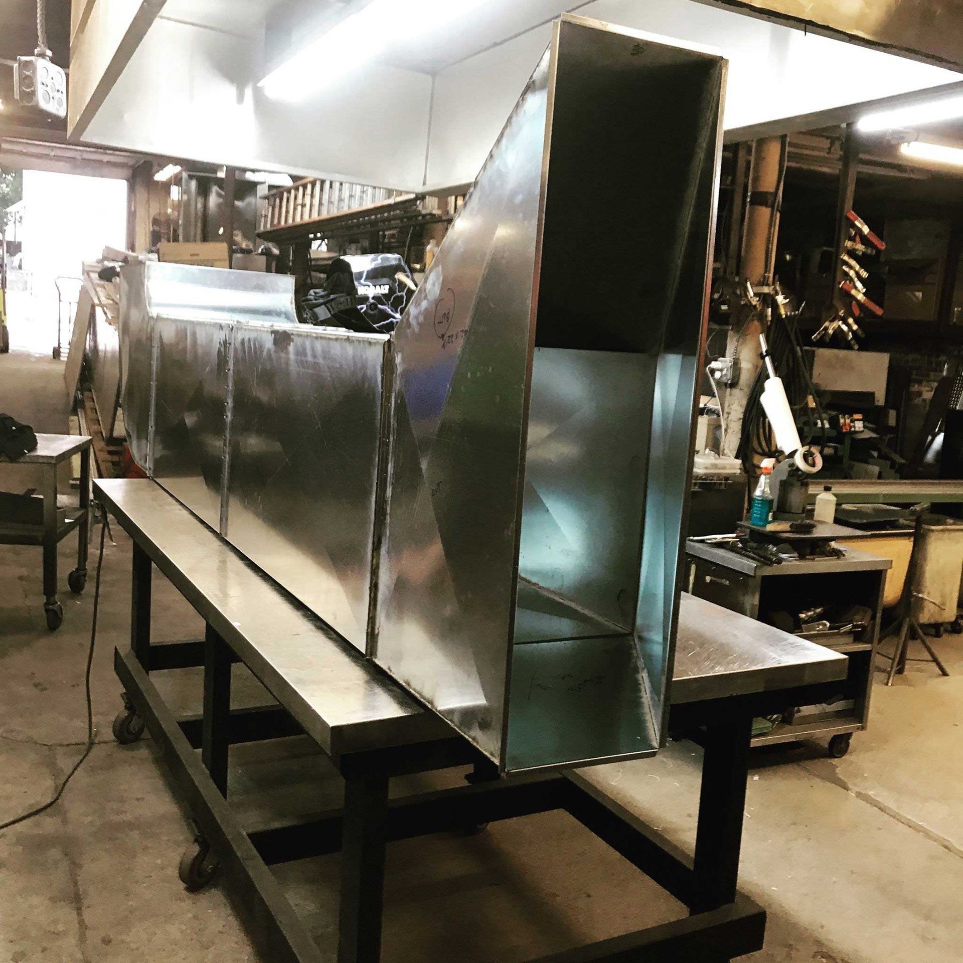A large metal pipe is sitting on top of a table in a factory.