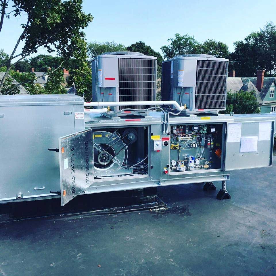 Two air conditioners are sitting on top of a roof with the doors open